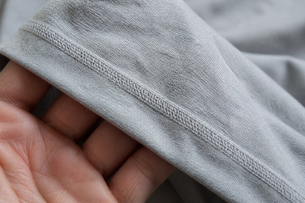 Close-up of a t-shirt seam showing flat-locked stitching with tight, even stitches in a professional garment, natural lighting highlighting the thread quality