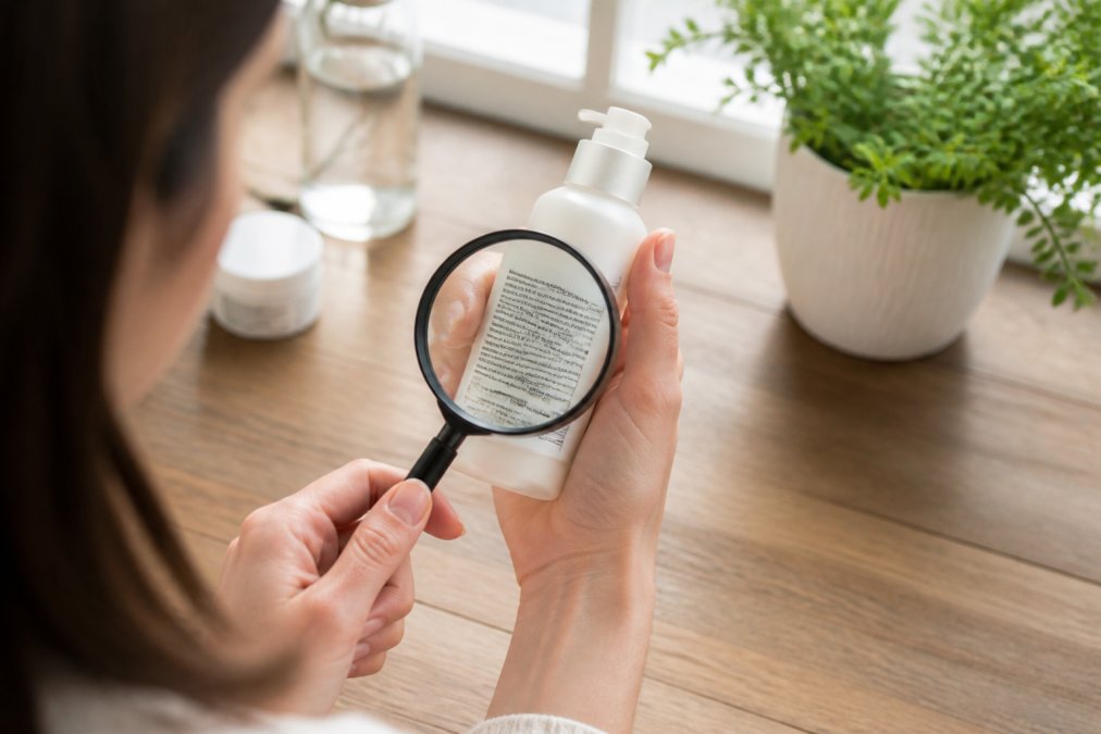 Close-up of hands holding a skincare product bottle, carefully reading the ingredient label with a magnifying glass in natural morning light