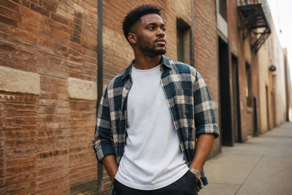 Young adult in a faith-inspired graphic tee and flannel, embodying a modern christian aesthetic in an urban setting.