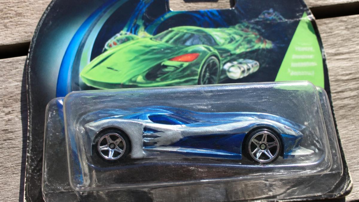 Close-up overhead view of an original AcceleRacers diecast car in sealed bubble packaging, showing card back details and bubble clarity under bright natural light