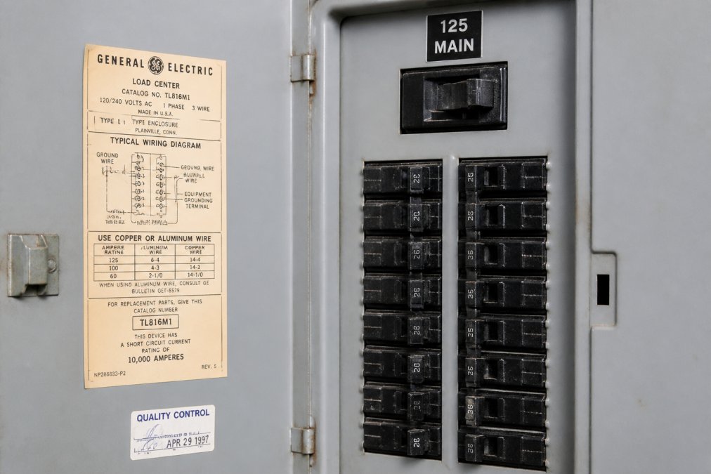 Close-up of an electrical panel door showing manufacturer label, breaker switches, and amperage rating clearly visible with professional lighting