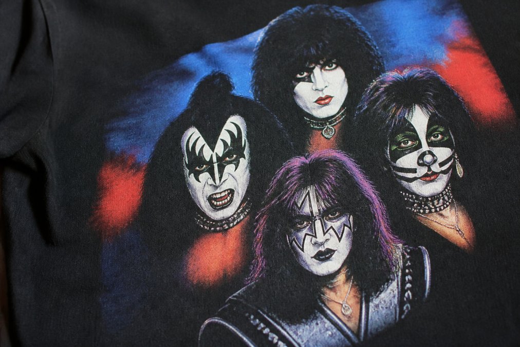 Detailed close-up of a band tee graphic showing crisp, vibrant print edges with no visible cracking or fading, the album artwork clearly defined against the fabric with natural daylight