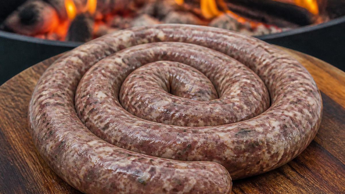 Infographic showing the coarse texture and spice blend of quality boerewors coiled on a wooden board