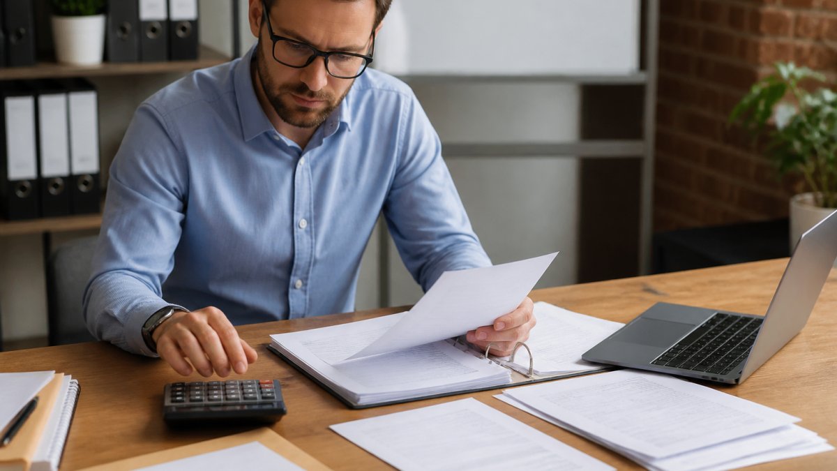 Business owner reviewing invoices and financial documents to improve business credit score through careful management