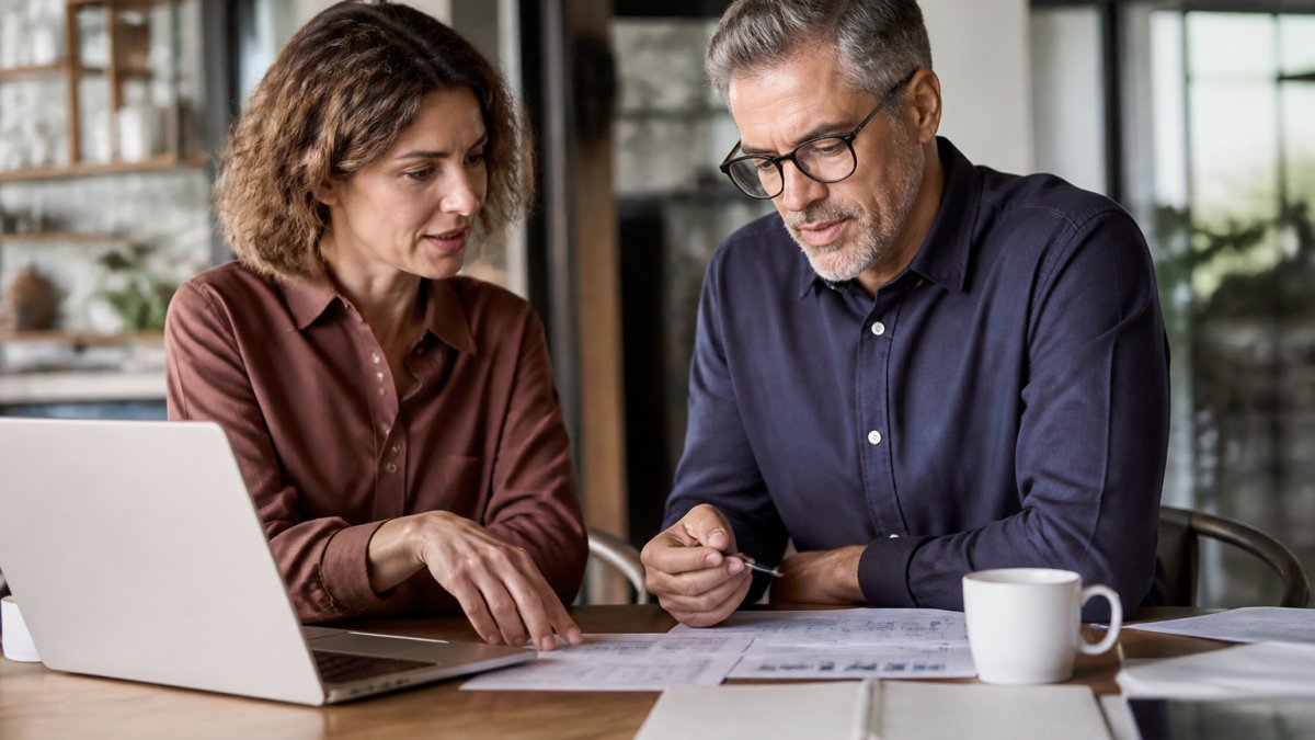 Small business owner and advisor reviewing a cash flow forecast on a laptop to improve cash flow together.
