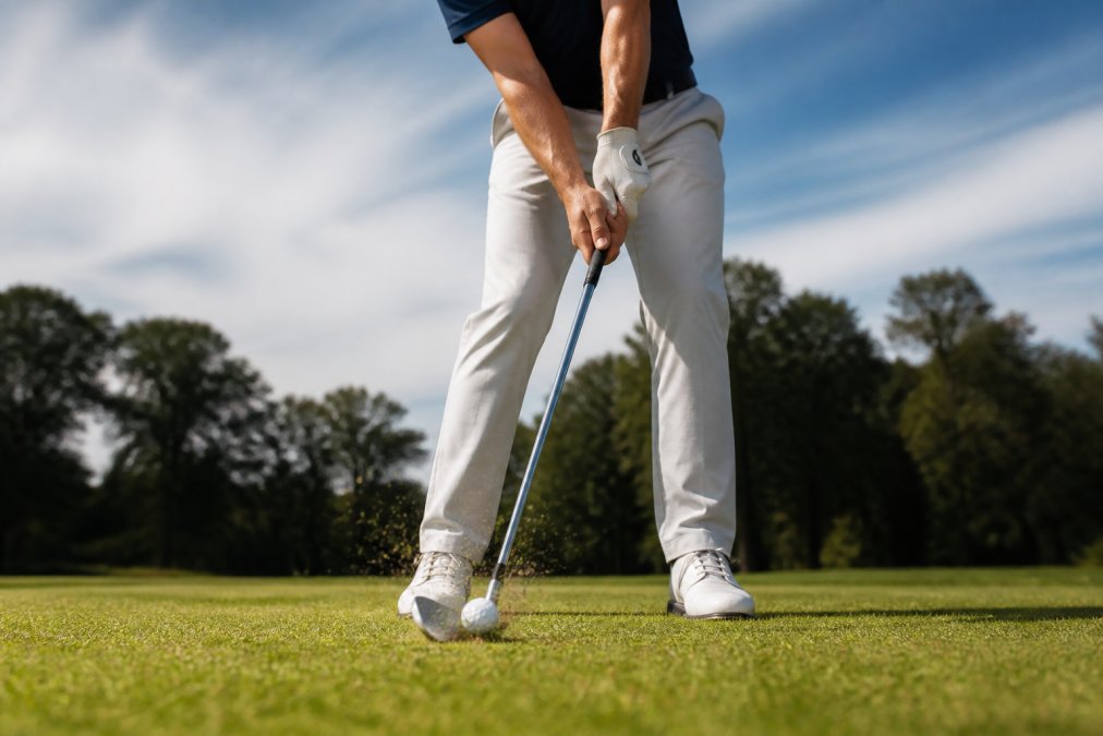 Professional golfer demonstrating proper impact position with hands forward and shaft lean at ball contact