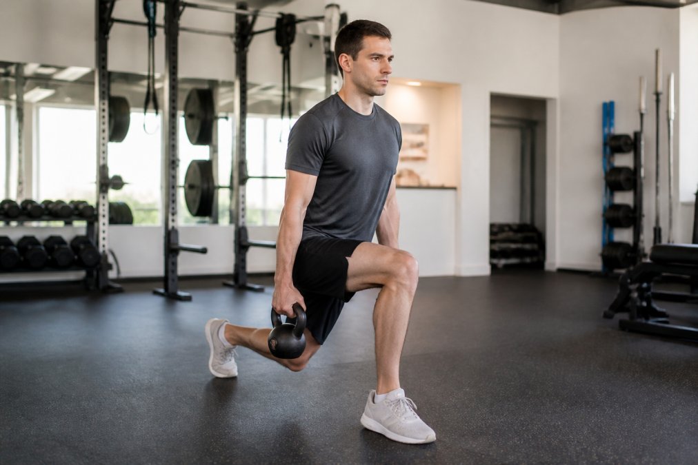 Golfer performing a kettlebell split squat in a gym to increase golf swing speed