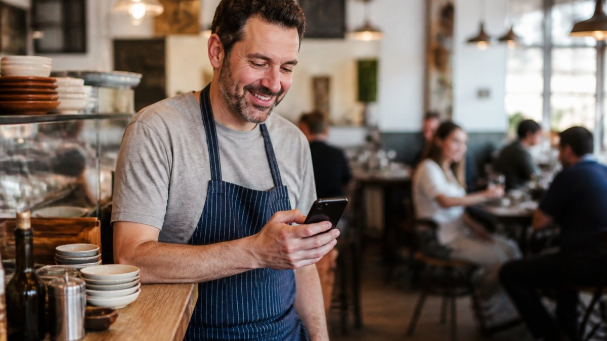 Restaurant owner smiling while checking customer reviews to improve online visibility