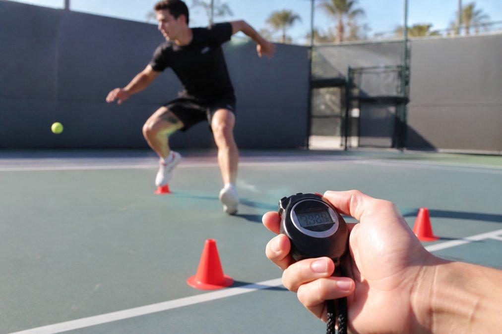 Competitive tennis player performing lateral agility drills to increase tennis court speed on a hard surface.
