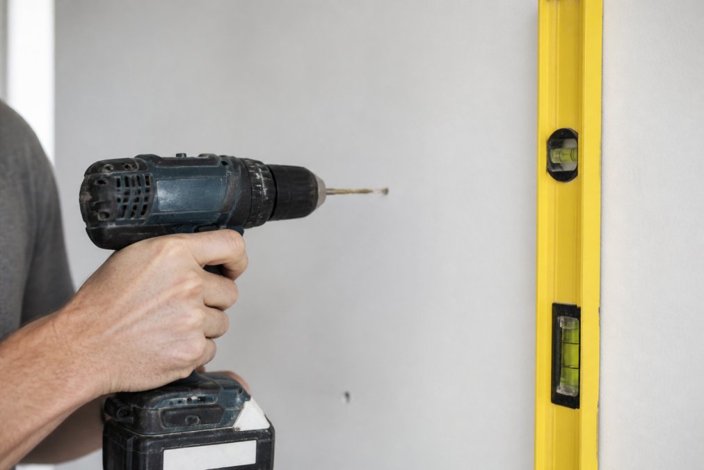 Step-by-step diagram showing how to drill pilot holes into drywall to install modular wine racks securely.