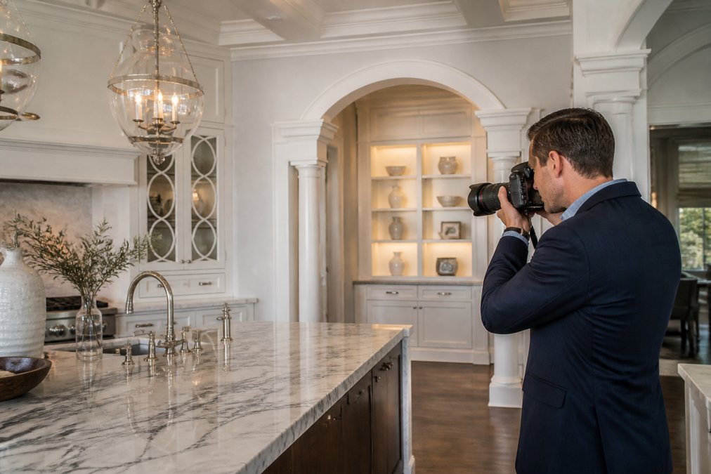 Professional home appraiser in business attire examining custom architectural details and premium finishes in a luxury home, photographing marble countertops, custom built-ins, and architectural moldings with professional camera