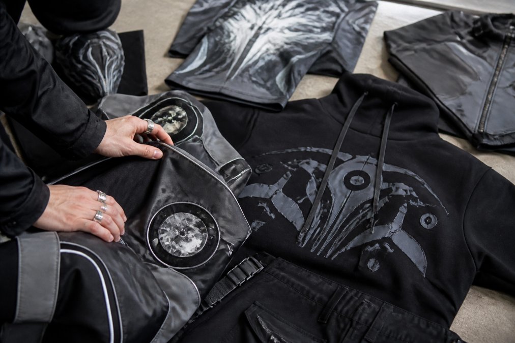 Close-up of hands arranging sci-fi themed apparel pieces on a flat surface, showing texture, color coordination, and design details