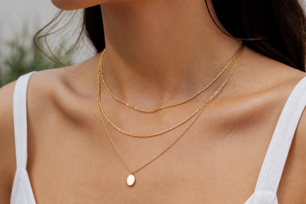 Woman wearing three gold layer necklaces of varying lengths around her neck and collarbone
