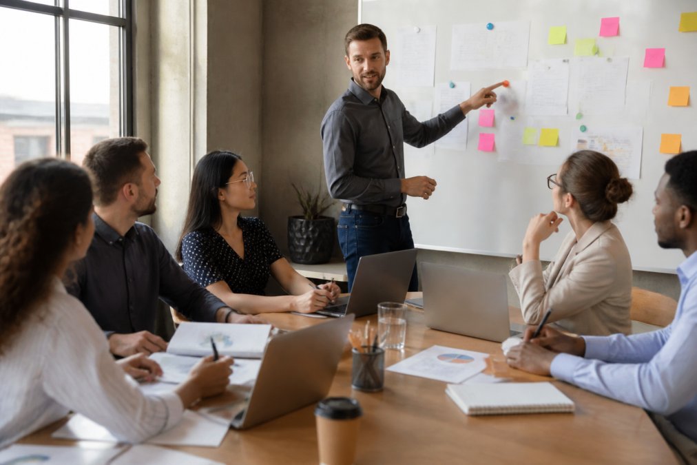 Diverse professionals collaborating on a workflow diagram for cross functional teams using sticky notes