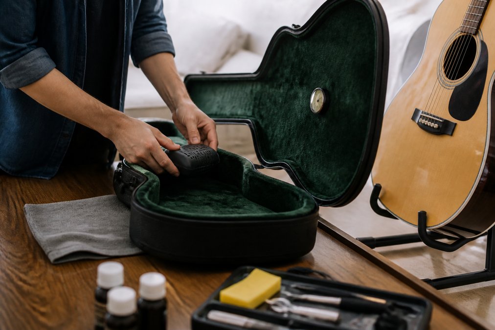 Musician placing a humidifier in a guitar case to regulate acoustic guitar humidity levels