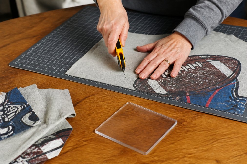 Step-by-step guide for using a rotary cutter and template to trim vintage sports t-shirts into fabric squares