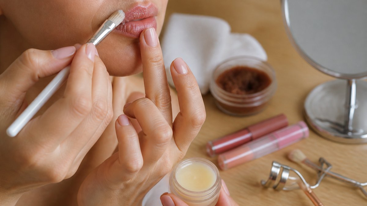 Close-up of hands gently exfoliating lips with a soft lip brush, followed by applying hydrating lip balm on fresh, smooth lips