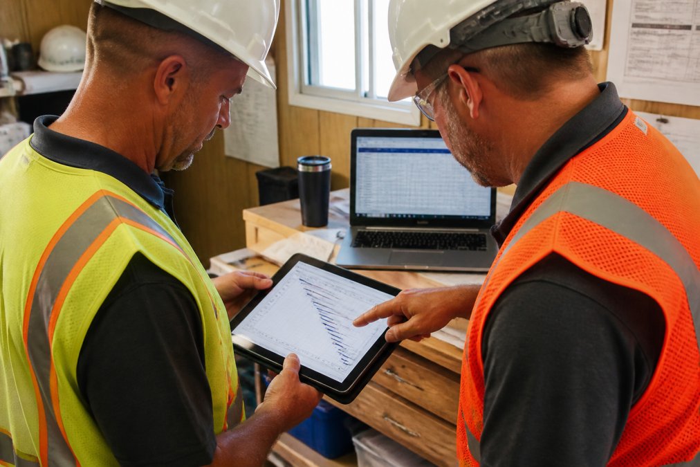 Project manager and superintendent reviewing a Gantt chart to resolve construction project delays on site.