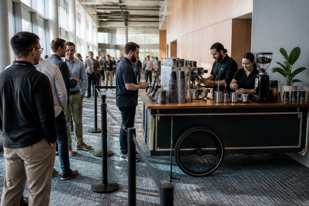 Baristas serving attendees at an organized station designed to prevent coffee lines in a bright venue space
