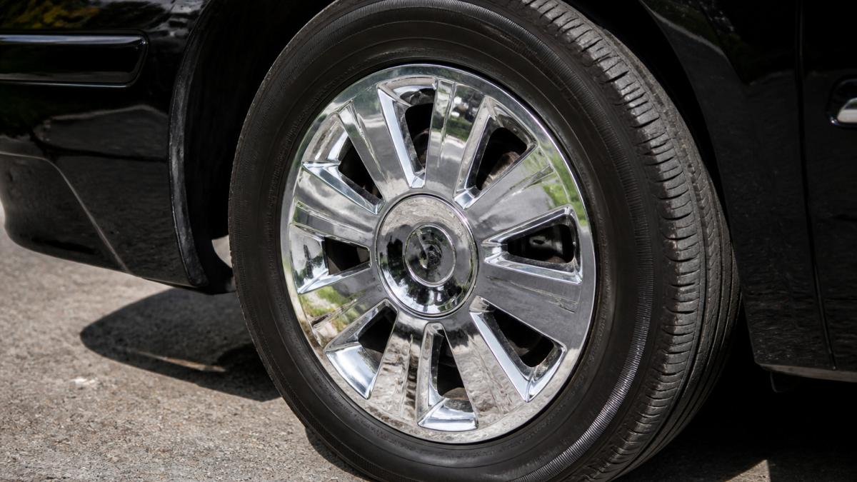 Polished chrome custom wheel covers reflecting sunlight while protecting a vehicle wheel from road debris.