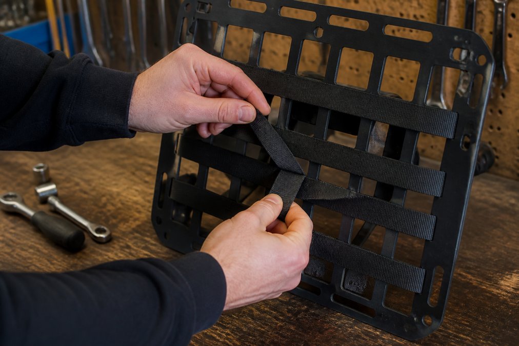 Step-by-step diagram showing the over-under weave pattern for attaching straps to rigid MOLLE panels.