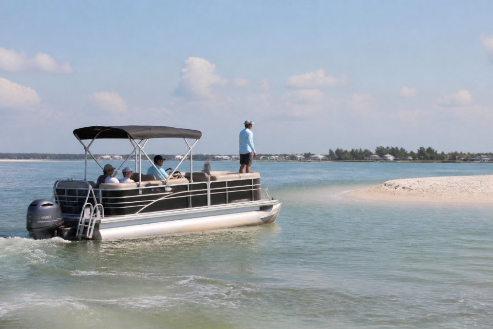 Pontoon boat navigating through shallow water at idle speed with a crew member posted at the bow scanning ahead, showing proper boat positioning and lookout awareness with calm water conditions