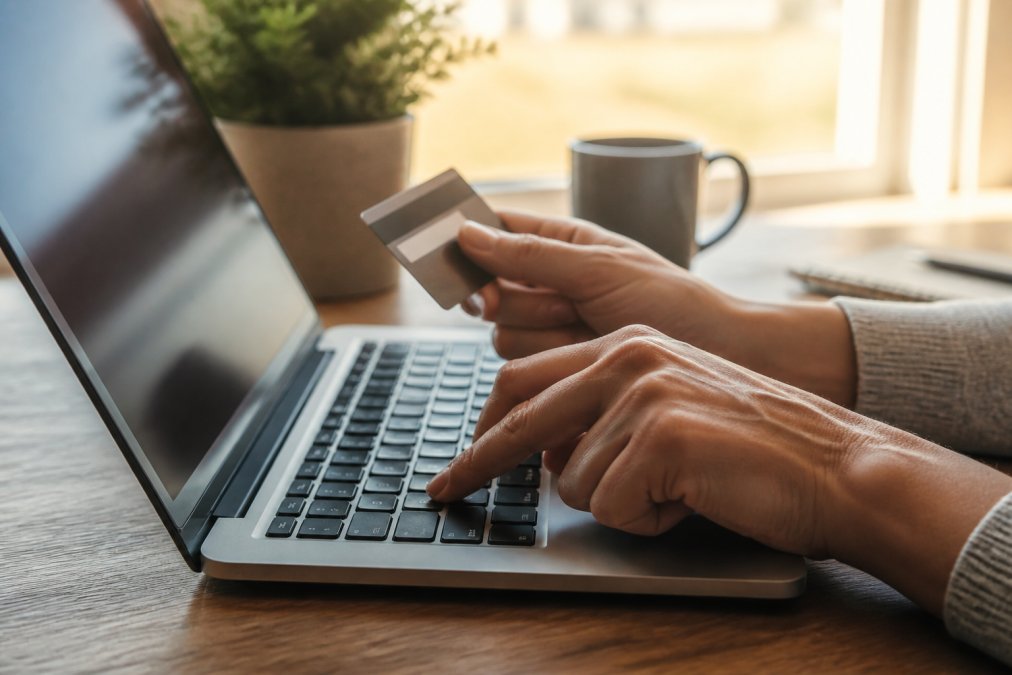 Close-up of hands entering payment information on a secure laptop with a visible padlock icon and "https://" in the address bar, warm office lighting