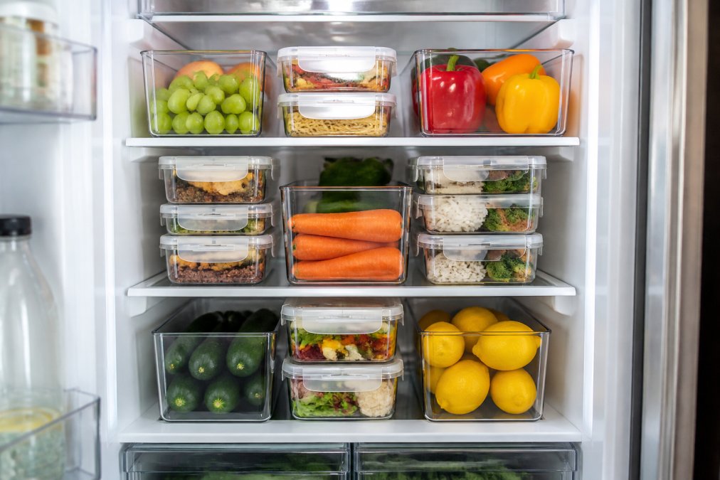 Interior view of refrigerator showing stacked acrylic bins and meal prep containers arranged vertically with clear visibility of contents, demonstrating efficient space use and easy access