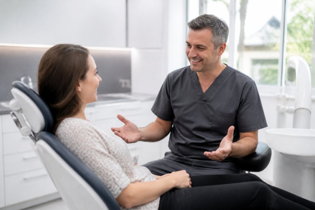 A patient sitting calmly in a dental chair having a friendly conversation with a smiling dentist in a modern, well-lit dental surgery, both relaxed and engaged