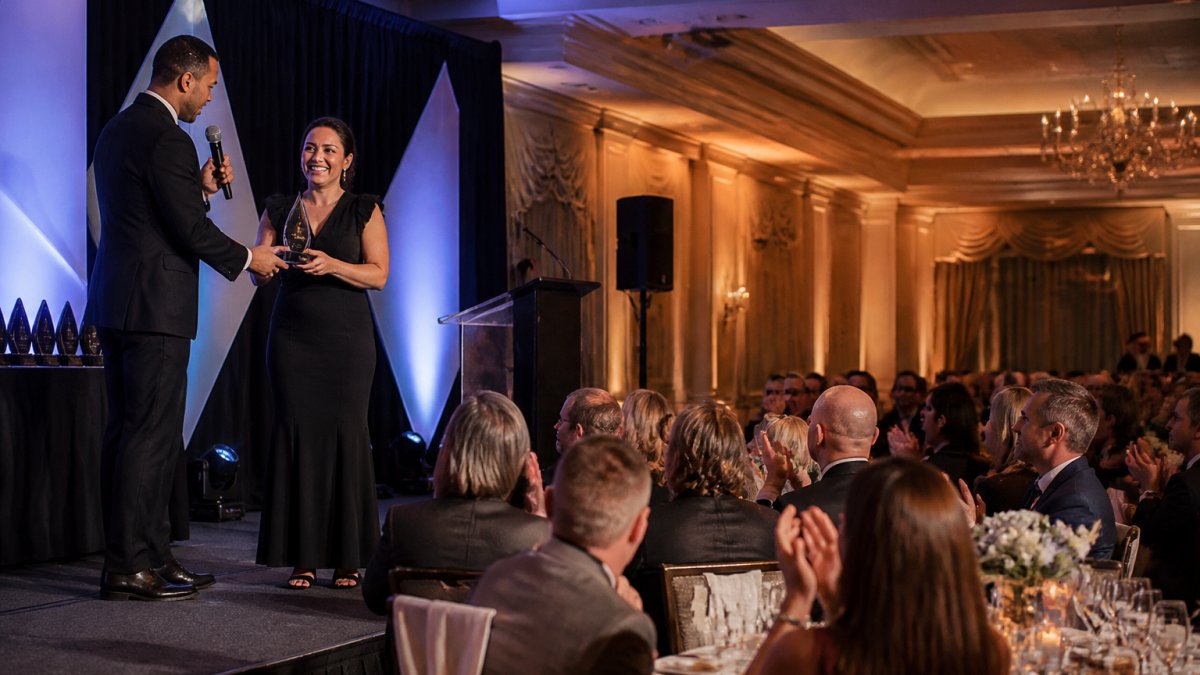 Emcee presenting an award to a smiling employee during a corporate awards ceremony in a banquet hall.