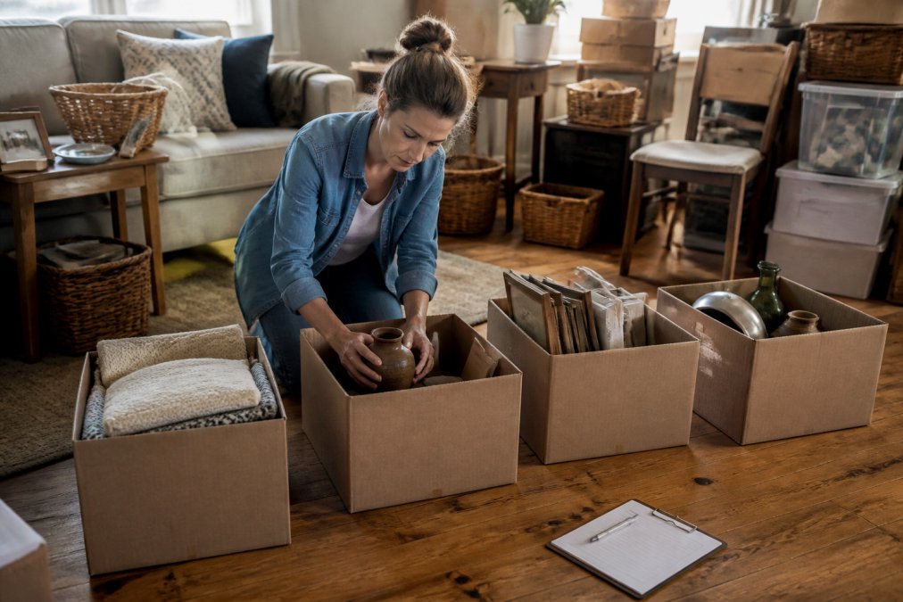 Person sorting household items into labeled boxes during an estate cleanout process