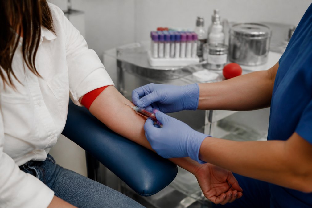 Close-up of phlebotomist collecting blood sample into labeled collection vials with proper technique and sterile equipment