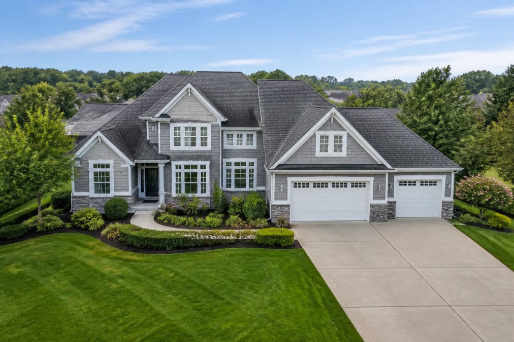 A well-maintained suburban home exterior with a freshly mowed lawn, trimmed hedges, and clear driveway, photographed from a slightly elevated angle showing the front yard and roofline