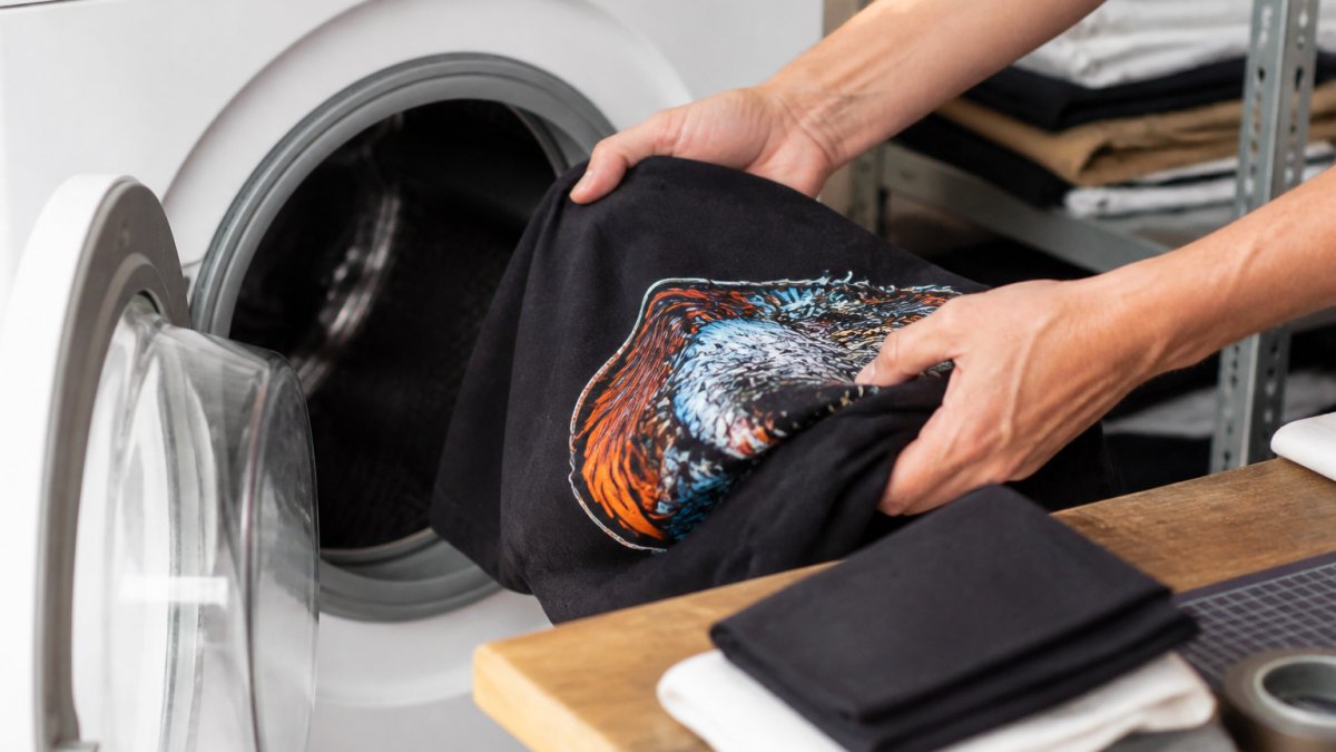 Hands turning a custom printed shirt inside out to prevent cracking printed shirts during a machine wash