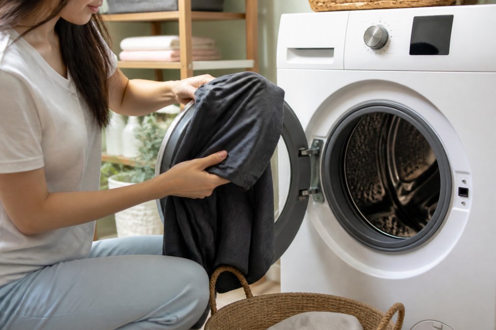 Hands turning a graphic tee inside out before a cold, gentle wash to prevent graphic tees from fading.