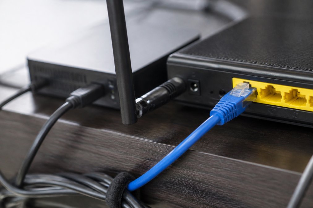 Close-up of ethernet cable connector plugged into router port alongside streaming device, showing stable wired connection setup with clear cable management