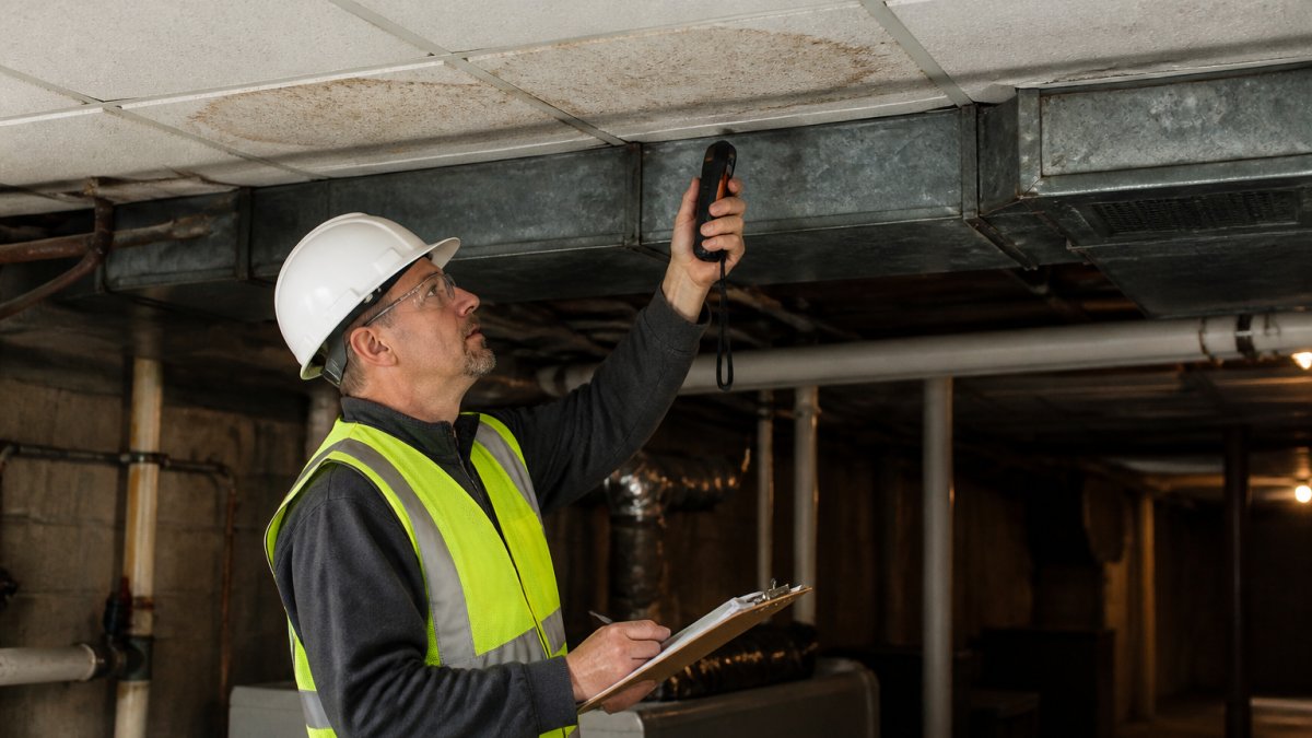 Facility manager using a moisture meter on ceiling tiles to learn how to prevent mold in commercial buildings