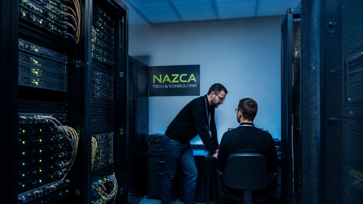 IT professionals monitoring server status and network health on multiple screens in a data center control room with blue lighting and organized equipment