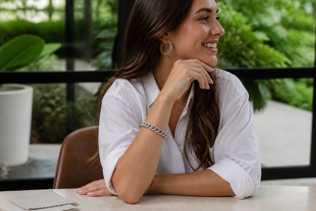 Woman wearing delicate sterling silver chain link bracelets and statement earrings during everyday activities in natural daylight, with a soft polishing cloth resting on a nearby table, showing the jewelry in active use