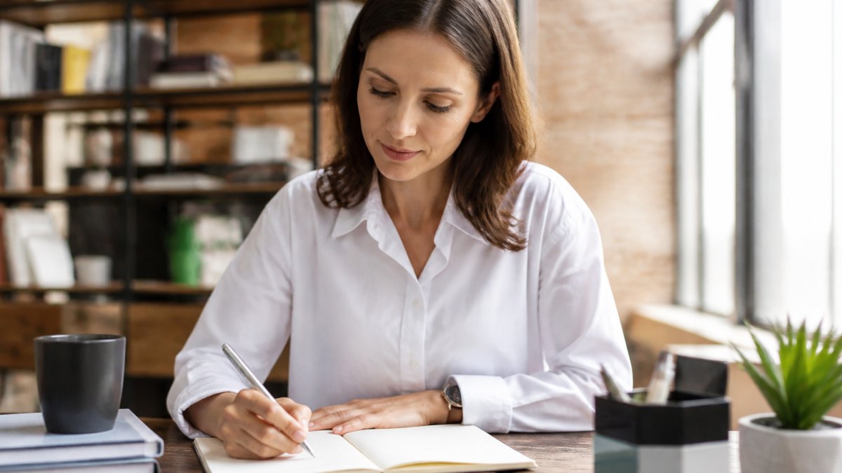 Professional focusing on a notebook at a clean desk to learn how to prioritize tasks to avoid workplace burnout