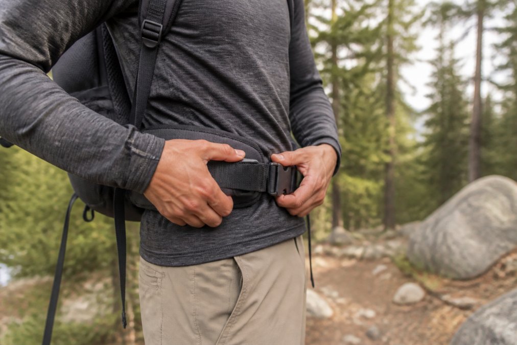 Hiker adjusting a padded backpack hip belt on their iliac crest to learn how to properly fit a multi-day backpacking pack.