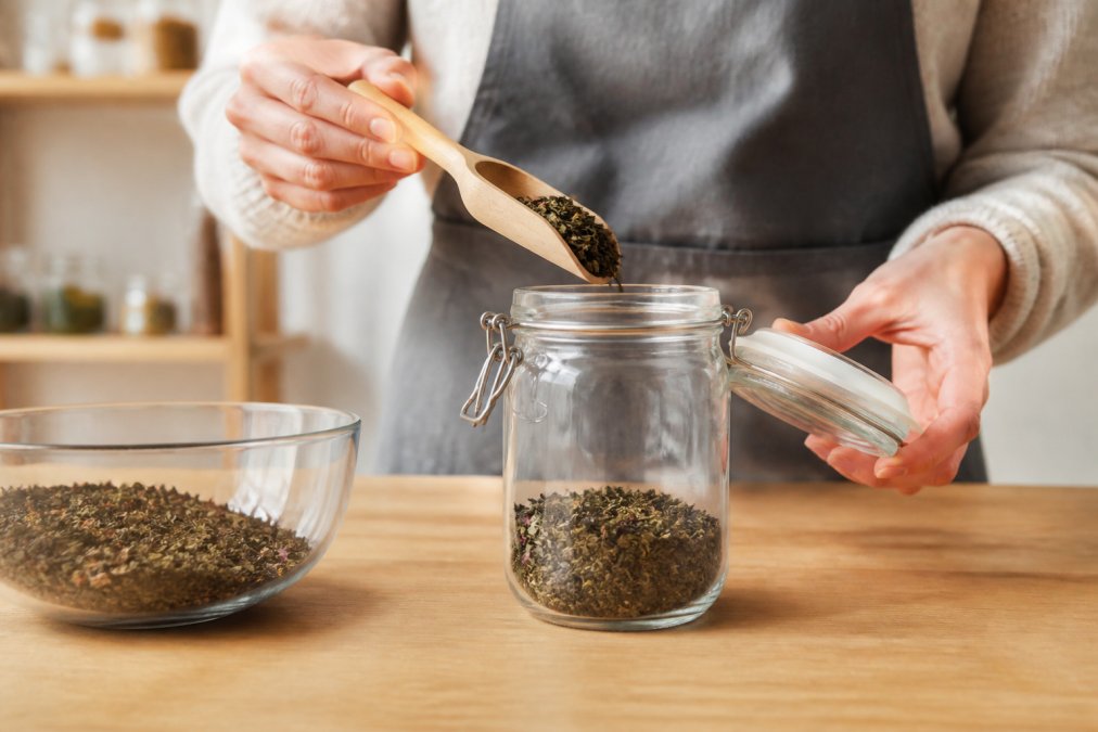 Step-by-step diagram showing how to store loose leaf tea in an airtight glass jar on a wooden surface