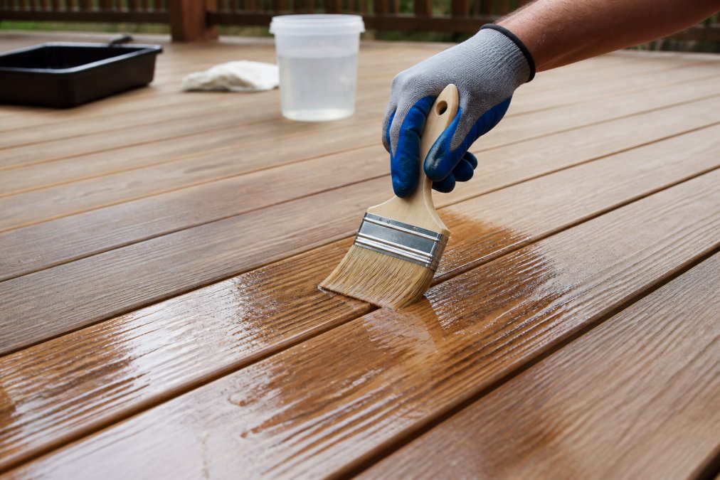 Step-by-step process of applying sealant to wood planks to prevent deck water damage