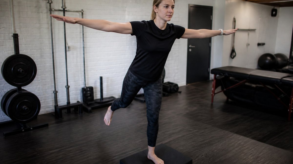 Athlete performing single-leg balance exercises to recover from skiing injuries in a gym setting