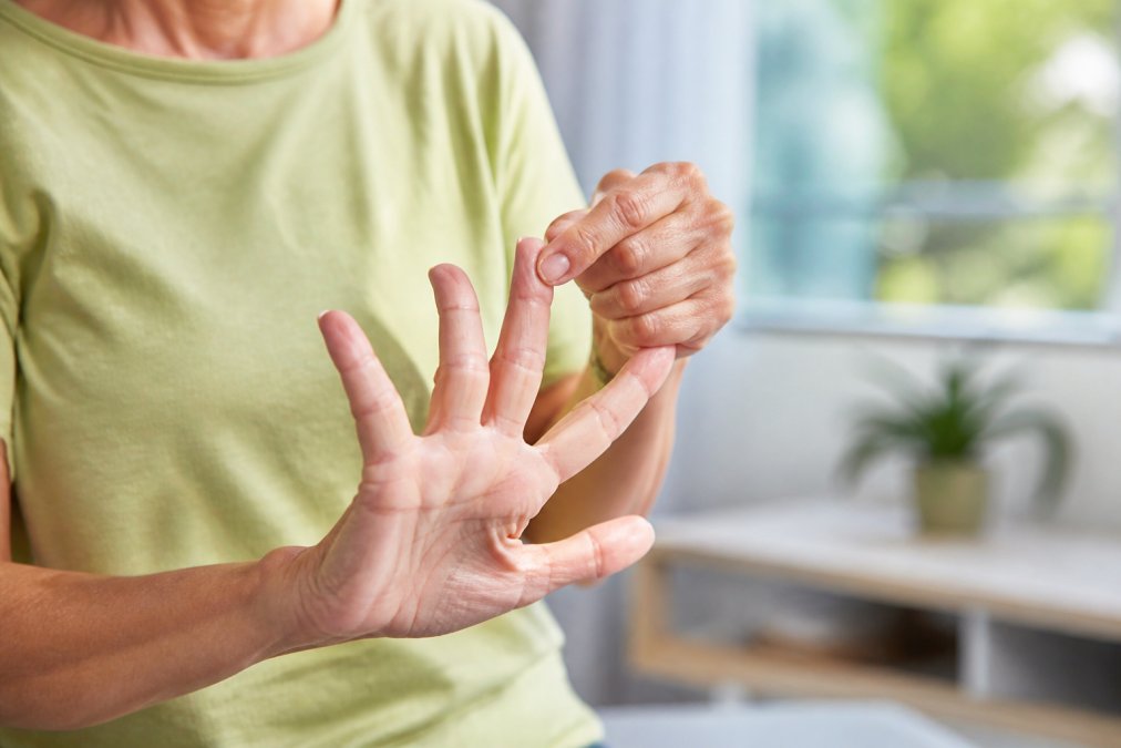 Close-up of hands performing gentle finger stretching and flexing exercises, with clear finger extension and relaxed posture, demonstrating proper technique in natural daylight