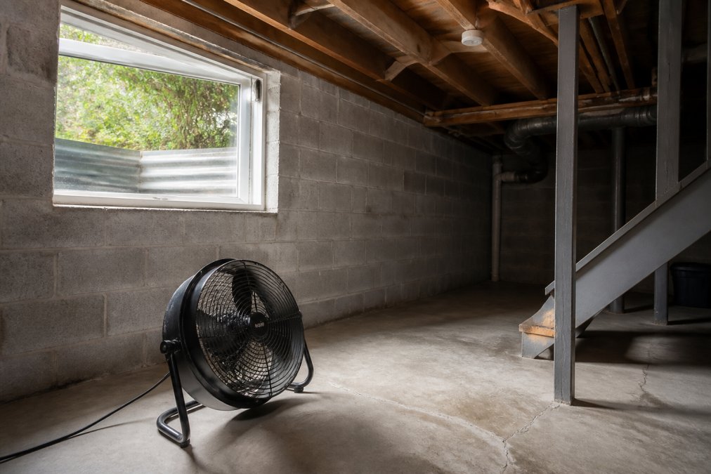 Diagram showing how to reduce humidity in basement naturally by positioning portable fans to improve air circulation
