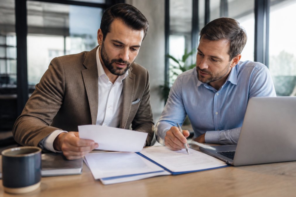 Two business partners reviewing a California general partnership legal form at a sunlit office desk