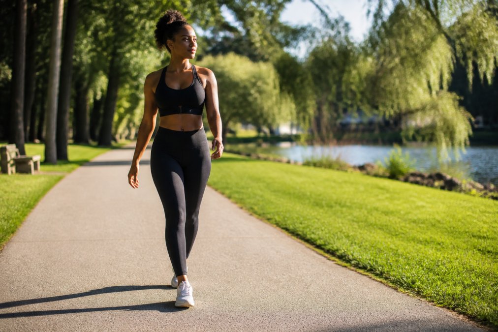 Woman performing gentle stretching outdoors in a park during morning light, demonstrating active recovery with relaxed posture and natural surroundings