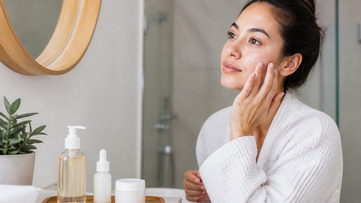 Person with sensitive skin applying moisturizer to repair a damaged skin barrier in a calm, bright bathroom.