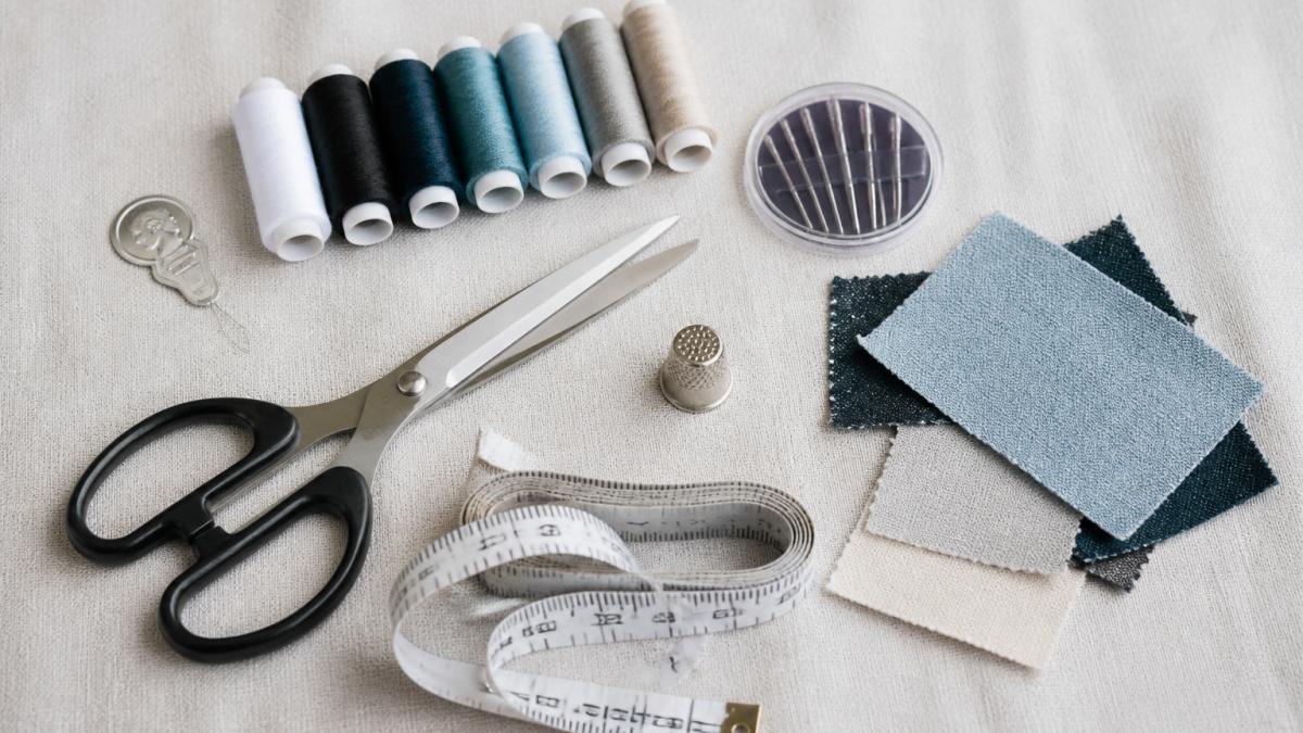 Essential sewing supplies including scissors, threads, and needles arranged neatly on fabric.